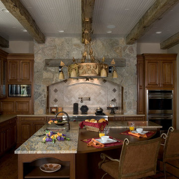 L-shaped island with stone accent wall and reclaimed barn beam details