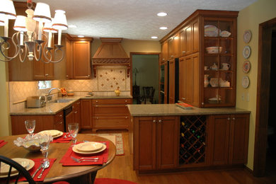 Example of a classic l-shaped medium tone wood floor eat-in kitchen design in Indianapolis with an undermount sink, recessed-panel cabinets, medium tone wood cabinets, granite countertops, paneled appliances and a peninsula