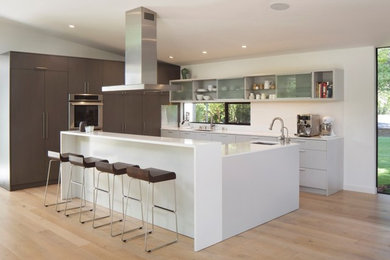 Eat-in kitchen - mid-sized modern l-shaped light wood floor and beige floor eat-in kitchen idea in San Francisco with flat-panel cabinets, gray cabinets, quartz countertops, white backsplash, glass sheet backsplash, paneled appliances and an island