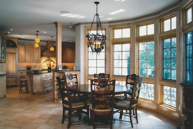 Photo of a large mediterranean kitchen/diner in New York with light wood cabinets, granite worktops, beige splashback, terracotta splashback, integrated appliances, porcelain flooring, an island and raised-panel cabinets.