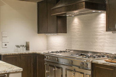 Example of a mid-sized transitional l-shaped light wood floor and beige floor enclosed kitchen design in Boston with dark wood cabinets, granite countertops, white backsplash, subway tile backsplash, stainless steel appliances, recessed-panel cabinets and a peninsula