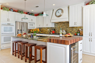 Inspiration for a timeless u-shaped beige floor kitchen remodel in San Diego with raised-panel cabinets, white cabinets, wood countertops, multicolored backsplash, matchstick tile backsplash, stainless steel appliances and an island