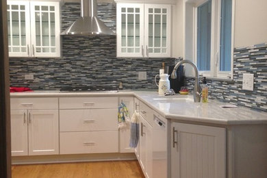 Example of a large trendy l-shaped light wood floor enclosed kitchen design in Chicago with an undermount sink, recessed-panel cabinets, white cabinets, quartzite countertops, blue backsplash, subway tile backsplash, stainless steel appliances and no island