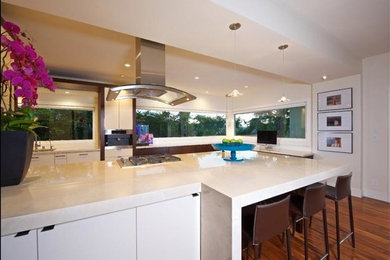 Foto på ett stort funkis kök, med marmorbänkskiva, rostfria vitvaror, mellanmörkt trägolv och en köksö