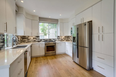 Mid-sized minimalist u-shaped light wood floor and brown floor eat-in kitchen photo in San Diego with an undermount sink, flat-panel cabinets, white cabinets, quartz countertops, black backsplash, glass tile backsplash, stainless steel appliances, no island and white countertops