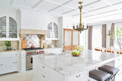 Inspiration for a large mediterranean l-shaped beige floor open concept kitchen remodel in San Diego with a farmhouse sink, recessed-panel cabinets, white cabinets, marble countertops, stainless steel appliances, an island and multicolored countertops