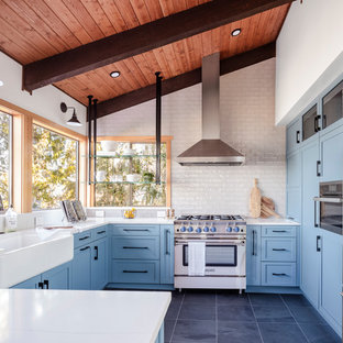 Diseño de cocina en U, de estilo de casa de campo, de tamaño medio, cerrada, con fregadero sobremueble, armarios estilo shaker, puertas de armario azules, electrodomésticos de acero inoxidable, suelo gris, encimeras blancas, salpicadero blanco, península, encimera de cuarzo compacto, salpicadero de azulejos tipo metro y suelo de baldosas de porcelana