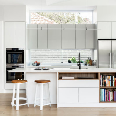 Beach style light wood floor kitchen photo in Sydney with an undermount sink, flat-panel cabinets, gray cabinets, window backsplash, stainless steel appliances, an island and white countertops