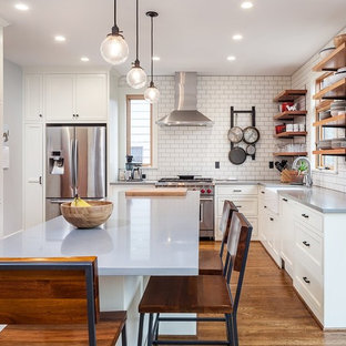 Design ideas for a mid-sized country l-shaped eat-in kitchen in Portland with a farmhouse sink, white cabinets, solid surface benchtops, white splashback, subway tile splashback, stainless steel appliances, with island, open cabinets, medium hardwood floors and brown floor.