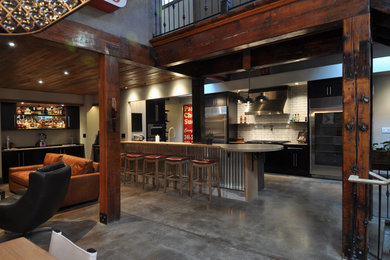 Inspiration for a large industrial u-shaped concrete floor and gray floor eat-in kitchen remodel in St Louis with a farmhouse sink, shaker cabinets, dark wood cabinets, wood countertops, white backsplash, subway tile backsplash, stainless steel appliances and a peninsula