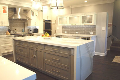 Inspiration for a large transitional dark wood floor and brown floor eat-in kitchen remodel in Chicago with a double-bowl sink, shaker cabinets, white cabinets, quartz countertops, gray backsplash, ceramic backsplash, stainless steel appliances, an island and white countertops