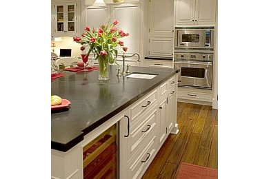 Inspiration for a large timeless u-shaped medium tone wood floor kitchen remodel in Los Angeles with a farmhouse sink, beaded inset cabinets, white cabinets, granite countertops, white backsplash, subway tile backsplash, stainless steel appliances and an island