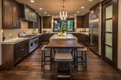 Inspiration for a rustic dark wood floor and brown floor kitchen remodel in Sacramento with shaker cabinets, dark wood cabinets, beige backsplash, stainless steel appliances and two islands