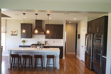 Mittelgroße Rustikale Küche mit Schrankfronten mit vertiefter Füllung, grauen Schränken, Quarzwerkstein-Arbeitsplatte, Küchenrückwand in Weiß und Kücheninsel in Detroit