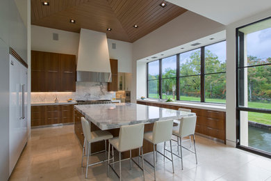 Example of a large trendy u-shaped travertine floor eat-in kitchen design in Austin with an undermount sink, flat-panel cabinets, medium tone wood cabinets, marble countertops, white backsplash, stone slab backsplash, white appliances and an island