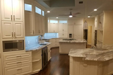 Large elegant kitchen photo in Houston with white cabinets, granite countertops, gray backsplash, two islands and gray countertops