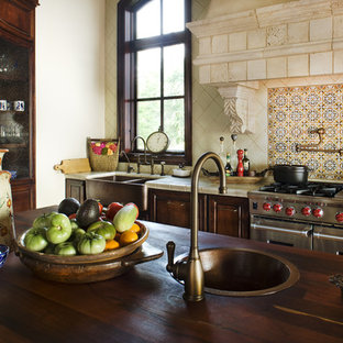Photo of a country kitchen in Austin with stainless steel appliances, a farmhouse sink, tile benchtops and multi-coloured splashback.