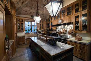 Example of a large arts and crafts u-shaped kitchen design in Chicago with recessed-panel cabinets, medium tone wood cabinets, white backsplash, stainless steel appliances, an island, an integrated sink and limestone countertops