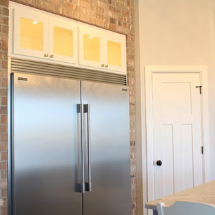 This is an example of a mid-sized country l-shaped open plan kitchen in Oklahoma City with a farmhouse sink, shaker cabinets, white cabinets, marble benchtops, white splashback, subway tile splashback, stainless steel appliances, ceramic floors and with island.