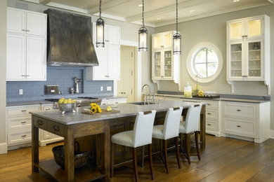 Transitional l-shaped light wood floor eat-in kitchen photo in Chicago with an undermount sink, recessed-panel cabinets, white cabinets, soapstone countertops, blue backsplash, ceramic backsplash, stainless steel appliances and an island