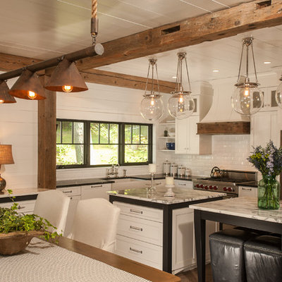 Mountain style l-shaped eat-in kitchen photo in New York with a farmhouse sink, shaker cabinets, white cabinets, granite countertops, white backsplash, subway tile backsplash and stainless steel appliances