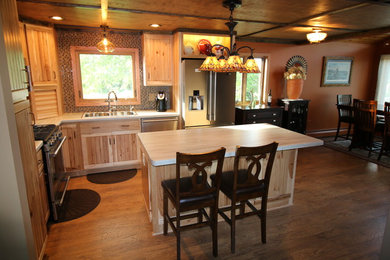 Inspiration for a mid-sized rustic l-shaped medium tone wood floor eat-in kitchen remodel in Other with a double-bowl sink, stainless steel appliances, an island, flat-panel cabinets, medium tone wood cabinets, soapstone countertops, multicolored backsplash and mosaic tile backsplash