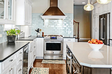 Example of a large transitional l-shaped dark wood floor eat-in kitchen design in Other with a farmhouse sink, recessed-panel cabinets, white cabinets, granite countertops, blue backsplash, subway tile backsplash, stainless steel appliances and an island