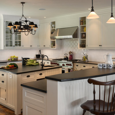 Elegant u-shaped kitchen photo in New York with a farmhouse sink, beaded inset cabinets, beige cabinets, white backsplash and stainless steel appliances