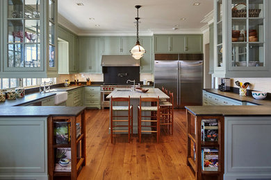 Inspiration for a timeless u-shaped medium tone wood floor kitchen remodel in New York with shaker cabinets, green cabinets, white backsplash, subway tile backsplash, an island and a farmhouse sink