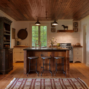 Mid-sized mountain style u-shaped medium tone wood floor kitchen photo in Burlington with shaker cabinets, white cabinets, wood countertops, white backsplash, stone tile backsplash, stainless steel appliances and an island