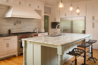 Example of a kitchen design in Atlanta with flat-panel cabinets, white cabinets, marble countertops and an island