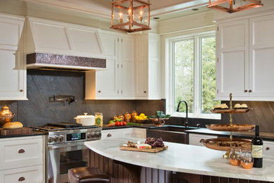 Example of a mid-sized classic l-shaped medium tone wood floor eat-in kitchen design in Boston with a farmhouse sink, recessed-panel cabinets, white cabinets, marble countertops, black backsplash, stone slab backsplash, stainless steel appliances and an island