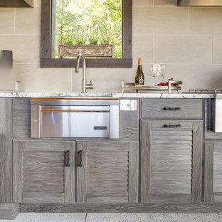 This is an example of an expansive contemporary l-shaped kitchen in Birmingham with a farmhouse sink, louvered cabinets, distressed cabinets, granite benchtops, stainless steel appliances and concrete floors.