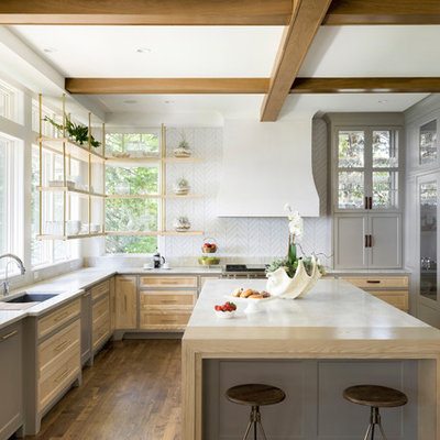 Cottage u-shaped medium tone wood floor and brown floor kitchen photo in Minneapolis with an undermount sink, recessed-panel cabinets, gray cabinets, white backsplash, paneled appliances, an island, white countertops and window backsplash