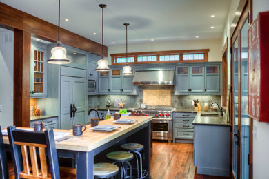 Foto på ett stort amerikanskt u-kök, med en undermonterad diskho, luckor med infälld panel, gröna skåp, träbänkskiva, grönt stänkskydd, stänkskydd i porslinskakel, rostfria vitvaror, mellanmörkt trägolv, en köksö och brunt golv