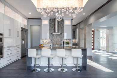 Example of a large trendy dark wood floor kitchen design in Charlotte with flat-panel cabinets, white cabinets, quartz countertops, multicolored backsplash, mosaic tile backsplash, stainless steel appliances and an island