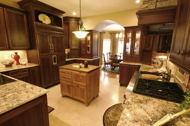 他の地域にある広いトラディショナルスタイルのおしゃれなキッチン (ドロップインシンク、中間色木目調キャビネット、御影石カウンター、白いキッチンパネル、パネルと同色の調理設備、セラミックタイルの床) の写真