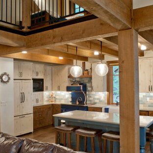 Design ideas for a country l-shaped kitchen in Other with an integrated sink, shaker cabinets, light wood cabinets, multi-coloured splashback, coloured appliances, medium hardwood floors, with island, brown floor and white benchtop.