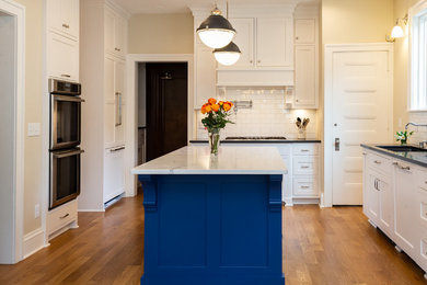 Eat-in kitchen - mid-sized transitional l-shaped light wood floor and brown floor eat-in kitchen idea in Minneapolis with marble countertops, white backsplash, an island, white countertops, an undermount sink, shaker cabinets, white cabinets, ceramic backsplash and stainless steel appliances