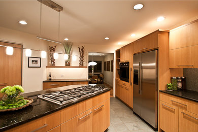 Imagen de cocina contemporánea abierta con fregadero bajoencimera, armarios con paneles lisos, puertas de armario de madera clara, encimera de granito, salpicadero gris y electrodomésticos de acero inoxidable