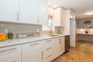 Inspiration for a small 1950s galley medium tone wood floor and brown floor eat-in kitchen remodel in Portland with an undermount sink, shaker cabinets, white cabinets, quartz countertops, gray backsplash, subway tile backsplash, stainless steel appliances and a peninsula