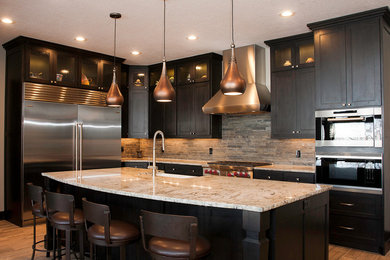 Example of a mid-sized transitional l-shaped porcelain tile and brown floor kitchen design in Salt Lake City with a farmhouse sink, shaker cabinets, dark wood cabinets, granite countertops, stone tile backsplash, stainless steel appliances, an island and brown backsplash