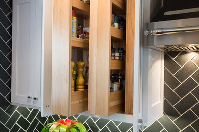 This is an example of a small traditional kitchen pantry in Kansas City with a single-bowl sink, shaker cabinets, white cabinets, quartz worktops, black splashback, glass tiled splashback, stainless steel appliances and medium hardwood flooring.