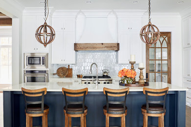 Example of a beach style dark wood floor kitchen design in Raleigh with shaker cabinets, white cabinets, white backsplash, stainless steel appliances, an island and white countertops