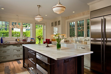 Mid-sized transitional l-shaped medium tone wood floor eat-in kitchen photo in Boston with a farmhouse sink, recessed-panel cabinets, green cabinets, marble countertops, beige backsplash and stainless steel appliances