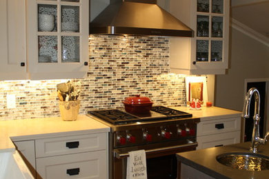 Inspiration for a mid-sized transitional l-shaped medium tone wood floor kitchen remodel in Toronto with a farmhouse sink, recessed-panel cabinets, white cabinets, quartzite countertops, multicolored backsplash, mosaic tile backsplash, stainless steel appliances and an island