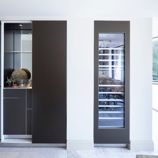 Design ideas for a large contemporary open plan kitchen in Cheshire with an integrated sink, flat-panel cabinets, medium wood cabinets, stainless steel benchtops, timber splashback, stainless steel appliances, ceramic floors, multiple islands, white floor and green benchtop.