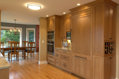 Example of a large transitional galley medium tone wood floor kitchen design in Seattle with an undermount sink, shaker cabinets, light wood cabinets, quartz countertops, ceramic backsplash, stainless steel appliances and an island