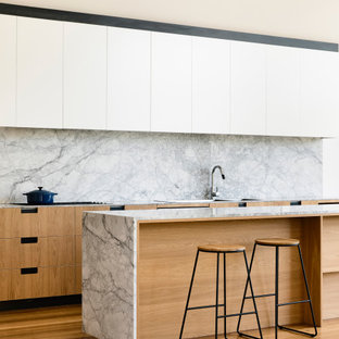 Inspiration for a contemporary galley kitchen in Geelong with flat-panel cabinets, white cabinets, grey splashback, stone slab splashback, medium hardwood floors, with island, brown floor and grey benchtop.