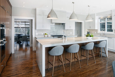 Inspiration for a large contemporary u-shaped medium tone wood floor eat-in kitchen remodel in Calgary with an undermount sink, shaker cabinets, white cabinets, quartzite countertops, gray backsplash, stone slab backsplash, stainless steel appliances and an island